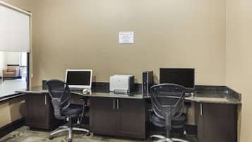 A hotel room with a desk, two chairs, a printer, and a large window.