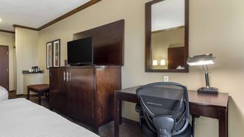 A hotel room with a bed, a desk, a chair, a TV, a wardrobe, and a mirror.