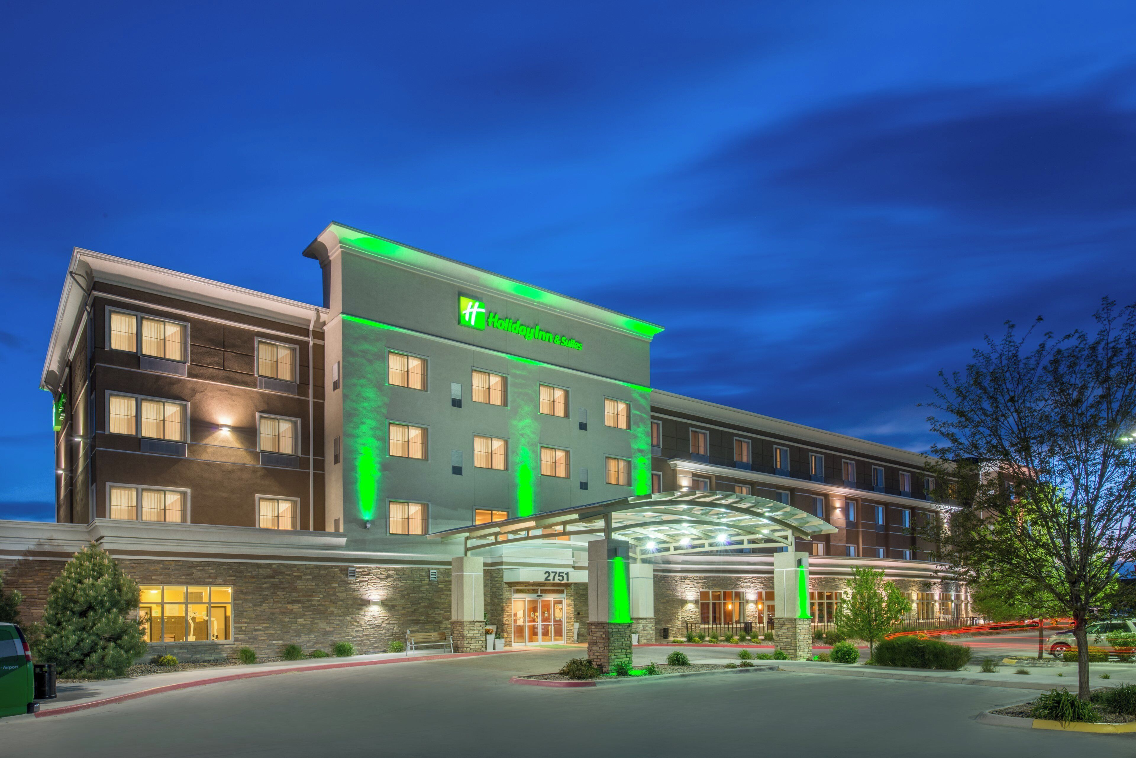 Un hotel Holiday Inn Express con una fachada moderna, un acceso cubierto y un área de estacionamiento bien iluminada.