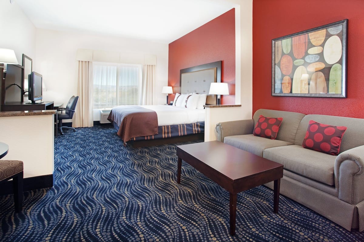 A hotel room with a bed, a sofa, a desk, and a TV.