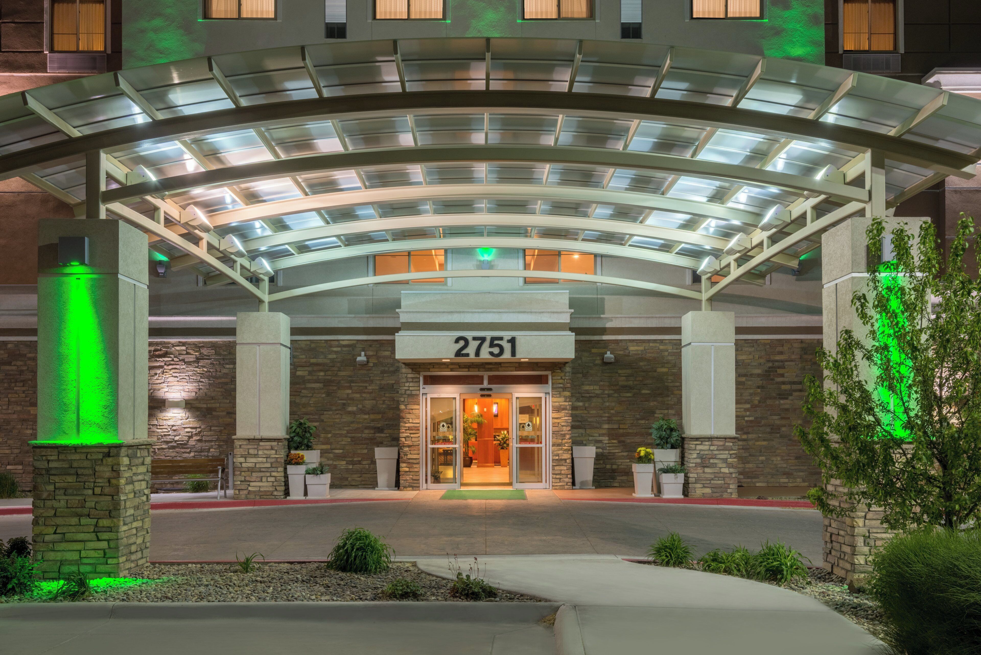 A hotel entrance with a covered walkway, stone facade, and a number sign.
