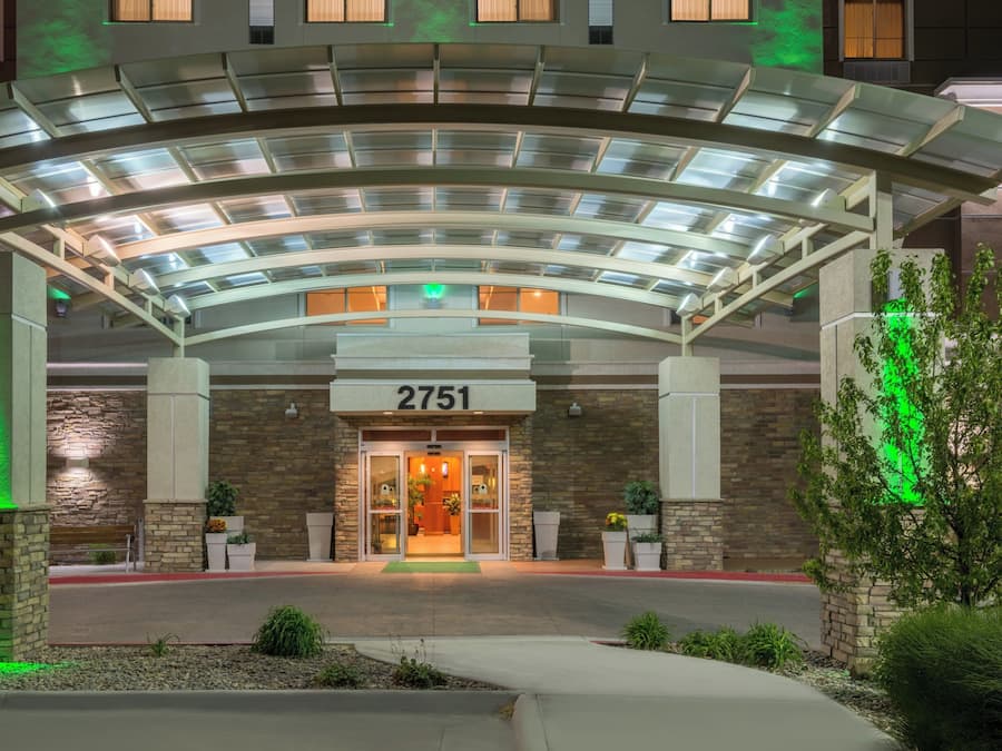 A hotel entrance with a covered walkway, stone facade, and a number sign.