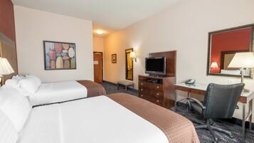 A hotel room with two beds, a desk with a computer, a chair, a television, and a painting on the wall.