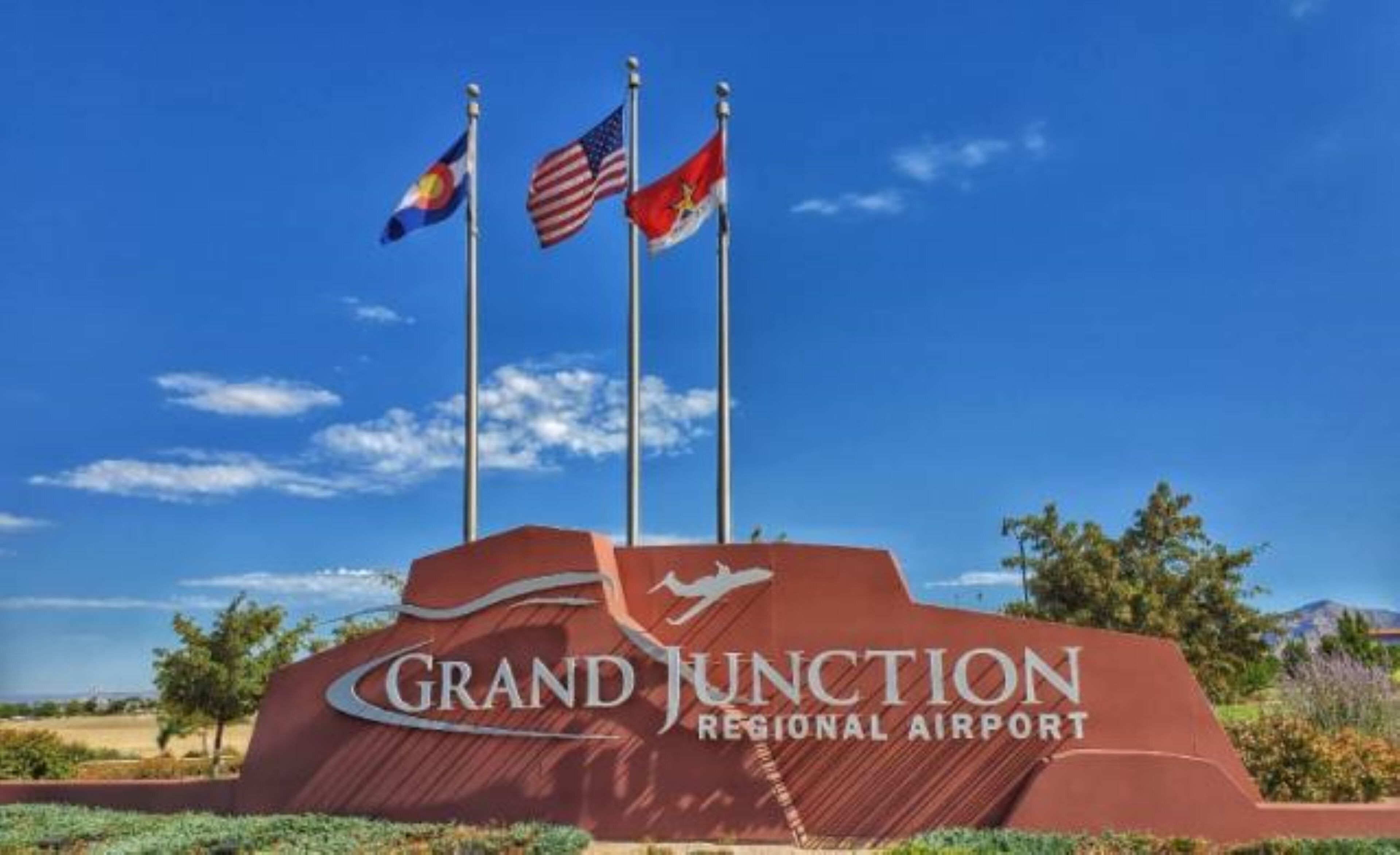 A sign for Grand Junction Regional Airport with three flags.