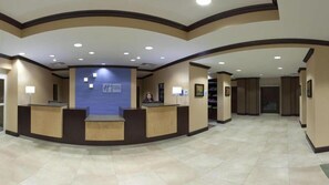 A reception area with a blue wall, a receptionist, and a reception desk. - Holiday Inn Express & Suites El Paso West by IHG (El Paso)