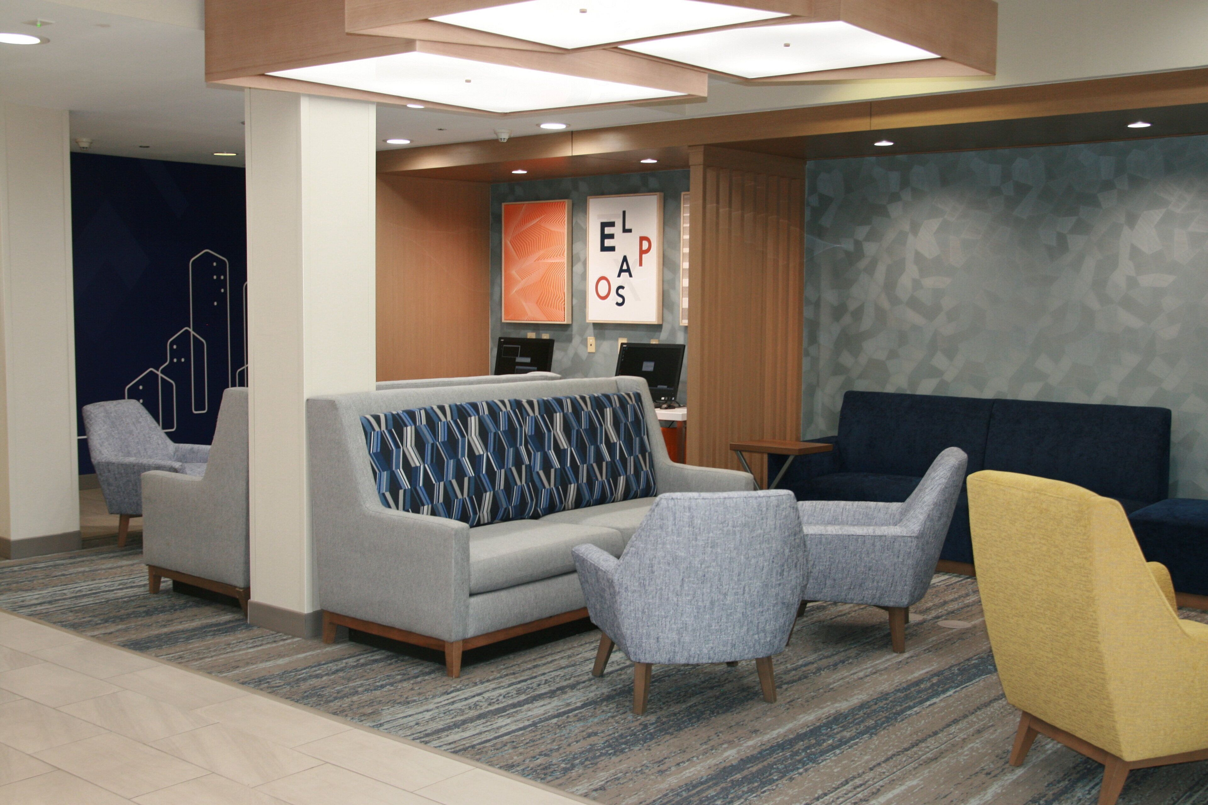 A lobby with a sofa, armchairs, a yellow chair, and a reception desk.