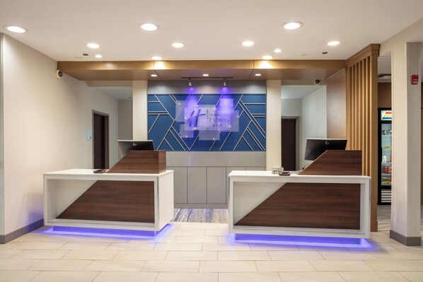 A reception area with two reception desks, a blue geometric wall design, and a visible fire alarm.