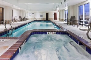 A swimming pool with a diving board, lounge chairs, and a lifeguard sign.