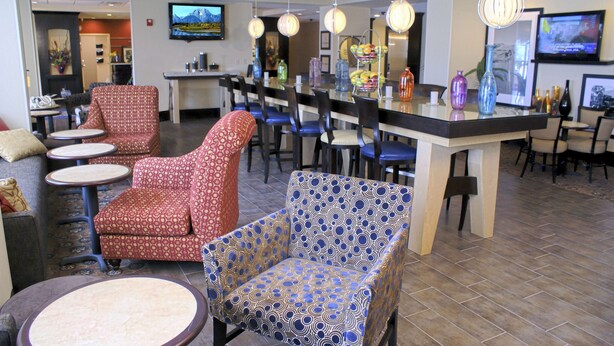 A hotel lobby with seating areas, a bar, and a television screen. - Hampton Inn Orange (Orange)