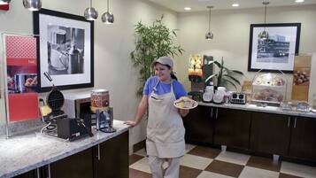 A kitchen area with a counter, appliances, and a person holding a plate.