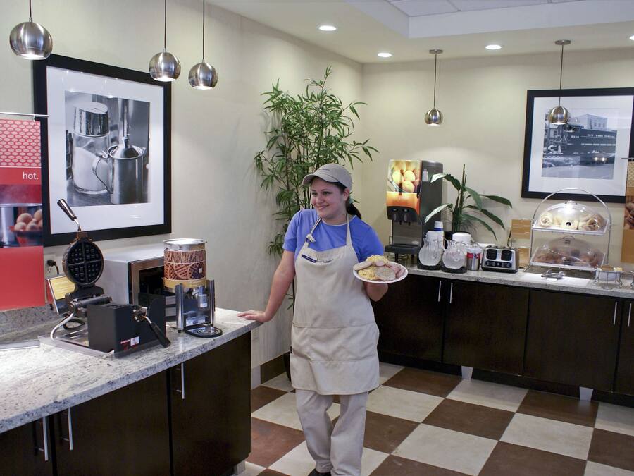 A kitchen area with a counter, appliances, and a person holding a plate.