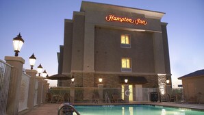 A Hampton Inn hotel with a swimming pool, outdoor seating, and a well-lit facade. - Hampton Inn Orange (Orange)
