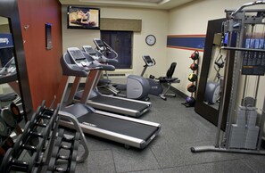 Un gimnasio con cintas de correr, bicicletas estáticas y máquinas de pesas.