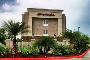 Edificio de Hampton Inn con fachada color crema, dos ventanas y un cartel sobre la entrada.