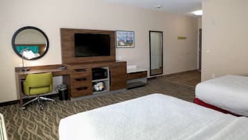Une chambre d’hôtel avec un lit, un bureau et une chaise, une télévision, un miroir et un tableau au mur.