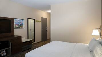 Quarto de hotel com uma cama, televisão, secretária e micro-ondas, e uma porta.