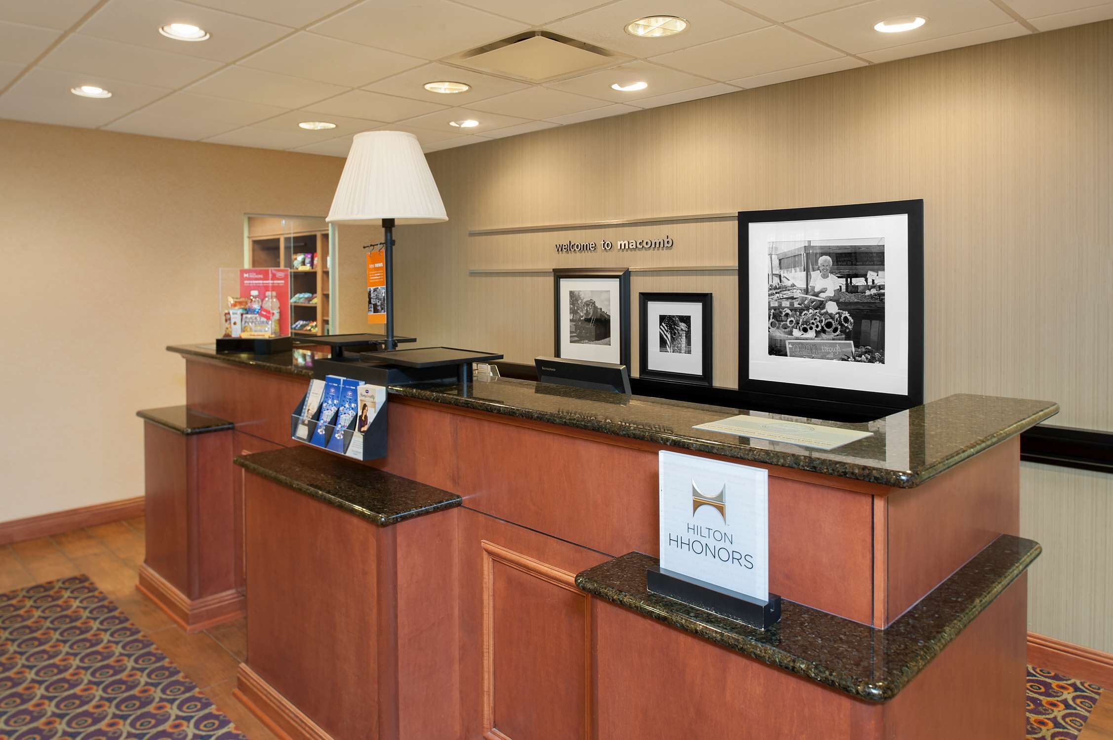 Un comptoir d’accueil avec une enseigne indiquant « Hilton HHONORS » et des photos encadrées accrochées au mur.