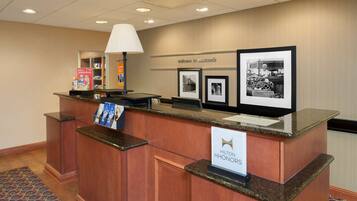 Un comptoir d’accueil avec une enseigne indiquant « Hilton HHONORS » et des photos encadrées accrochées au mur.