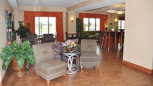 A spacious lobby with a dining area, multiple seating options, and large windows.