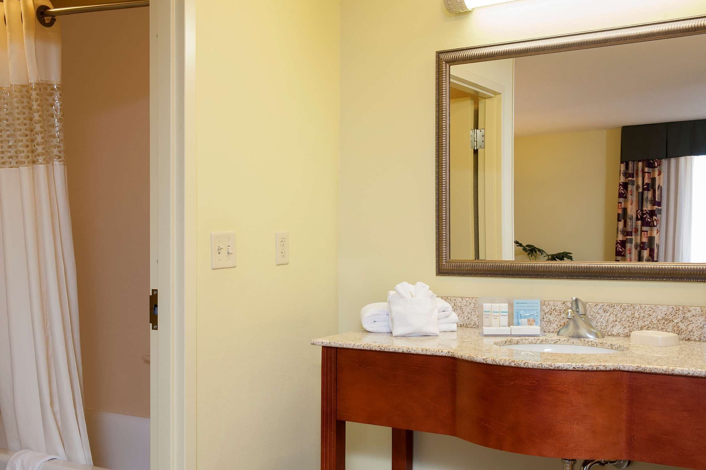 A bathroom with a sink, mirror, and towel rack.