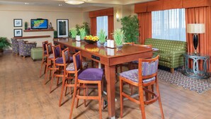 A hotel room with a dining area, a green sofa, and a TV on the wall.