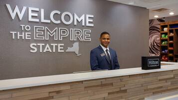 Un mostrador de recepción con un cartel que dice "WELCOME TO THE EMPIRE STATE" y un cartel de "Hilton Honors".