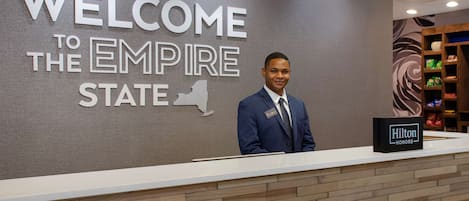 Una reception con un cartello che dice 'WELCOME TO THE EMPIRE STATE' e un cartello 'Hilton Honors'.