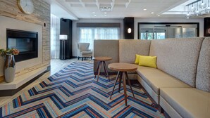 Een moderne woonkamer met een open haard, een bank, twee bijzettafeltjes en een vloerkleed met een patroon.