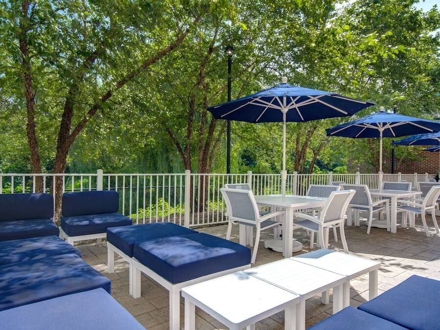 An outdoor patio with white furniture, blue cushions, and blue umbrellas.