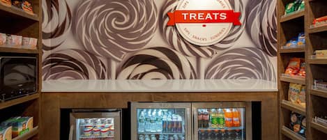 A wall with a swirl pattern and a sign that says "Treats". Below, there are three beverage refrigerators.