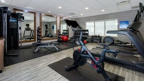 Een fitnessruimte met cardiotoestellen, krachtherinneringen en spiegels.