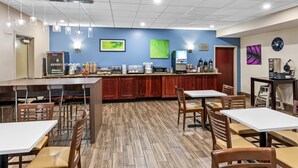 A restaurant with a central bar area, wooden flooring, and a blue wall with artwork. - Sleep Inn & Suites Hiram - Atlanta Northwest (Hiram)