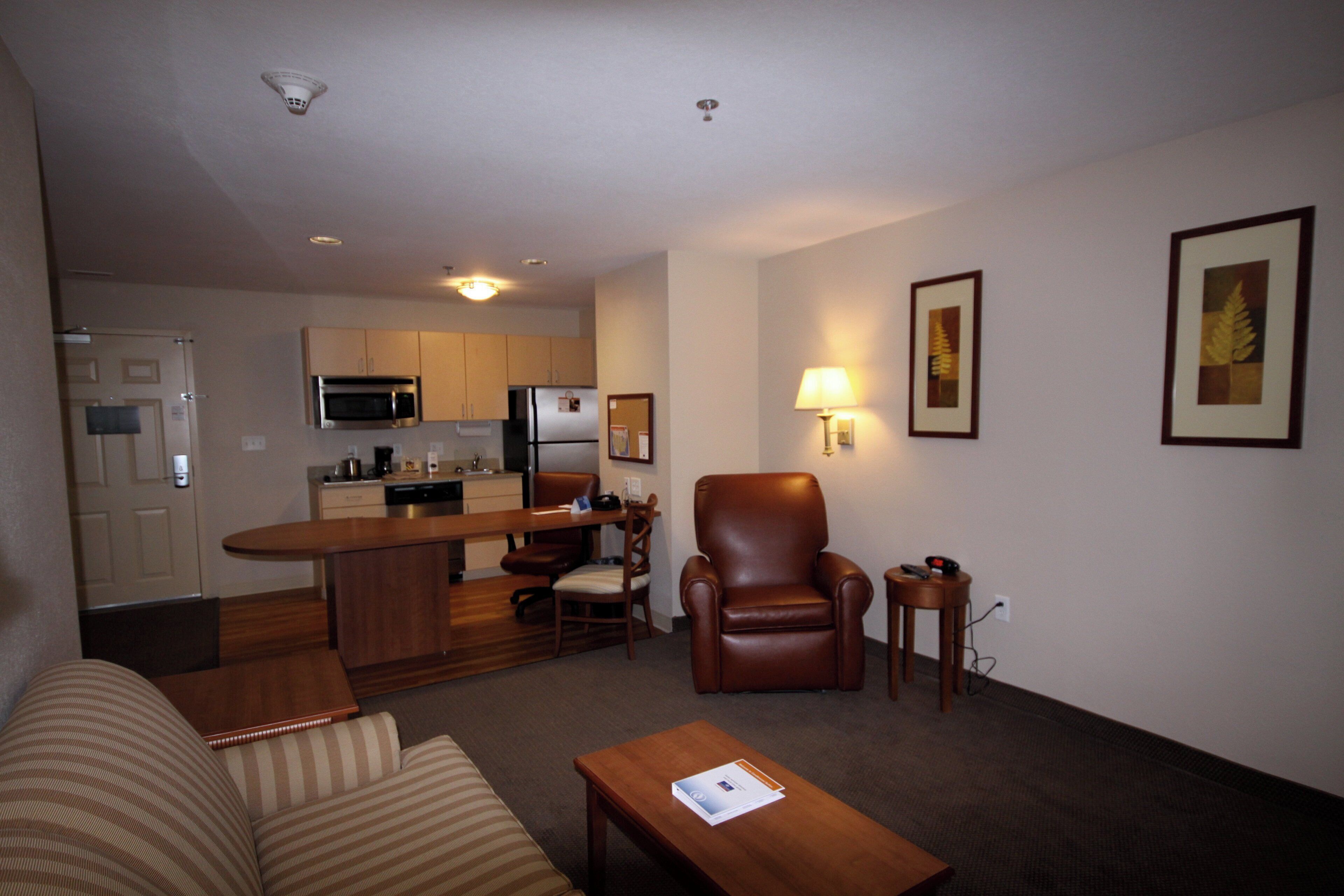 A compact living space with a kitchenette, a dining area, a sofa, a chair, and a small table.