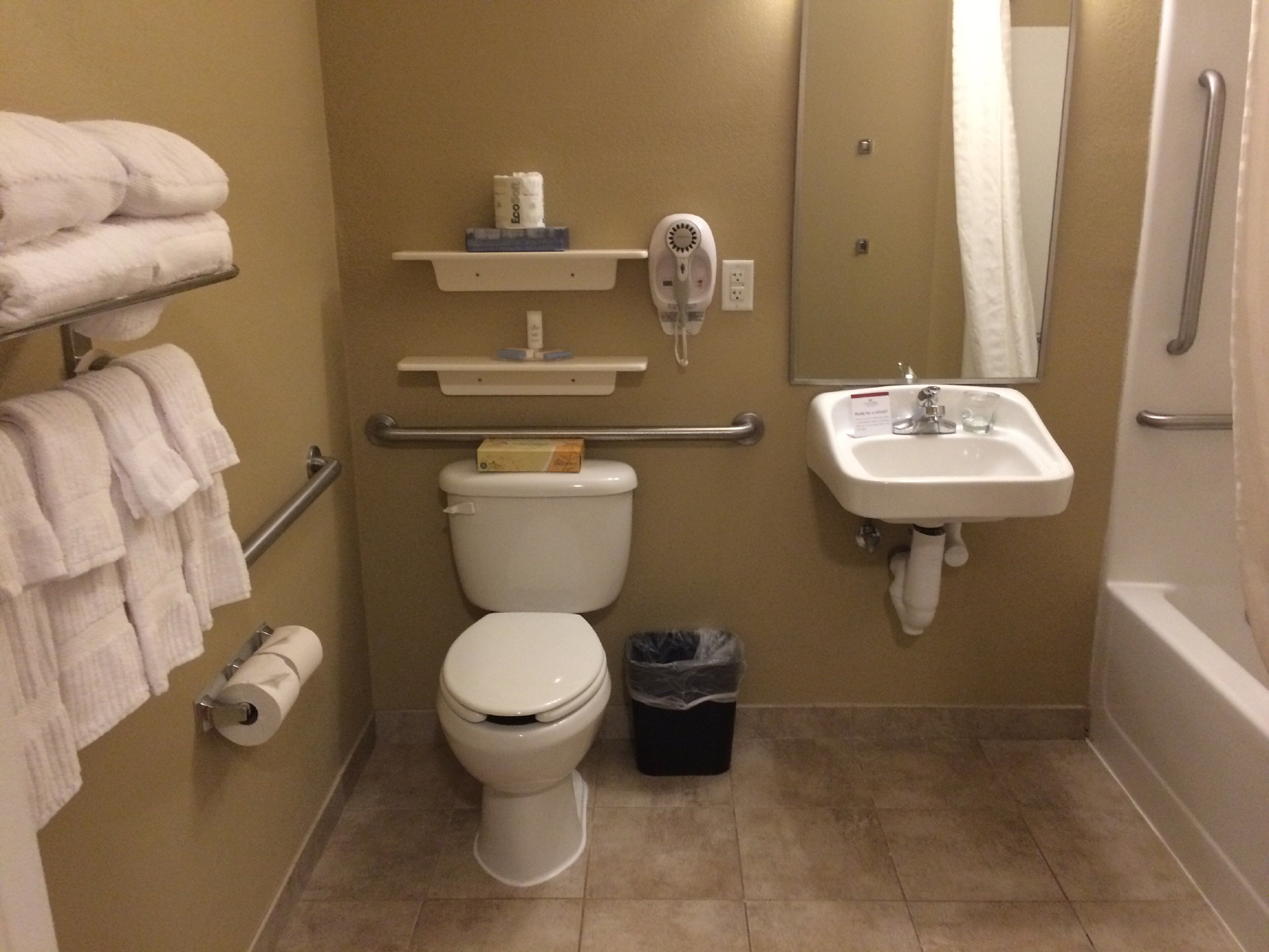 Une salle de bain équipée d’un WC, d’un lavabo, d’une poubelle, d’un porte-serviettes et d’un sèche-mains.