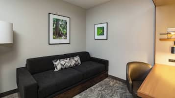 A modern room with a dark grey sofa, a wooden table, and two framed pictures on the wall.