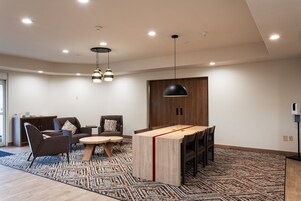 Una sala de estar moderna con zona de comedor, que incluye una mesa de madera, dos sofás y una alfombra estampada.