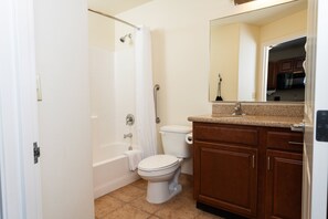 Une salle de bain avec une baignoire, des toilettes et des meubles en bois.
