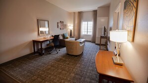 A hotel room with a carpeted floor, a desk with a chair, a sofa, a TV, and a lamp. - Sonesta ES Suites Baton Rouge University at Southgate (Baton Rouge)