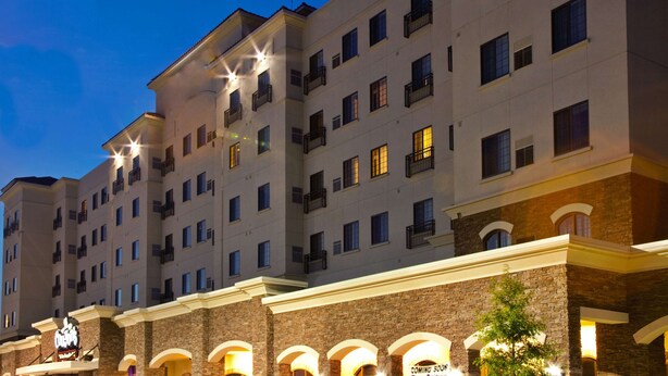 A multi-story hotel with a prominent entrance featuring a sign and arched windows. - Sonesta ES Suites Baton Rouge University at Southgate (Baton Rouge)