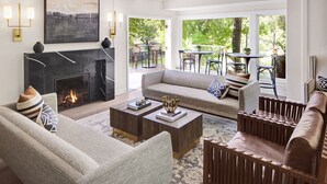 A modern living room with a fireplace, comfortable seating, and a view of the outdoors.