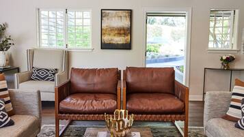 A living room with a brown leather sofa, a patterned armchair, and a decorative gold bowl on a coffee table.