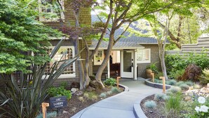 A house with a garden, a pathway leading to the entrance, and a sign indicating a lobby.
