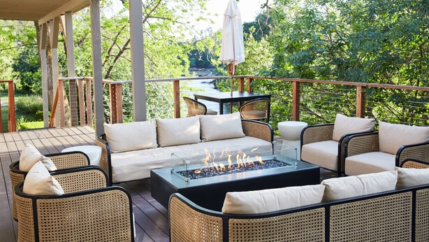 An outdoor patio with wicker furniture, a fire pit, and a view of a natural landscape.