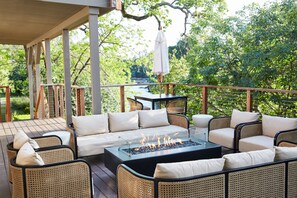 An outdoor patio with wicker furniture, a fire pit, and a view of a natural landscape. - Milliken Creek Inn (Napa)