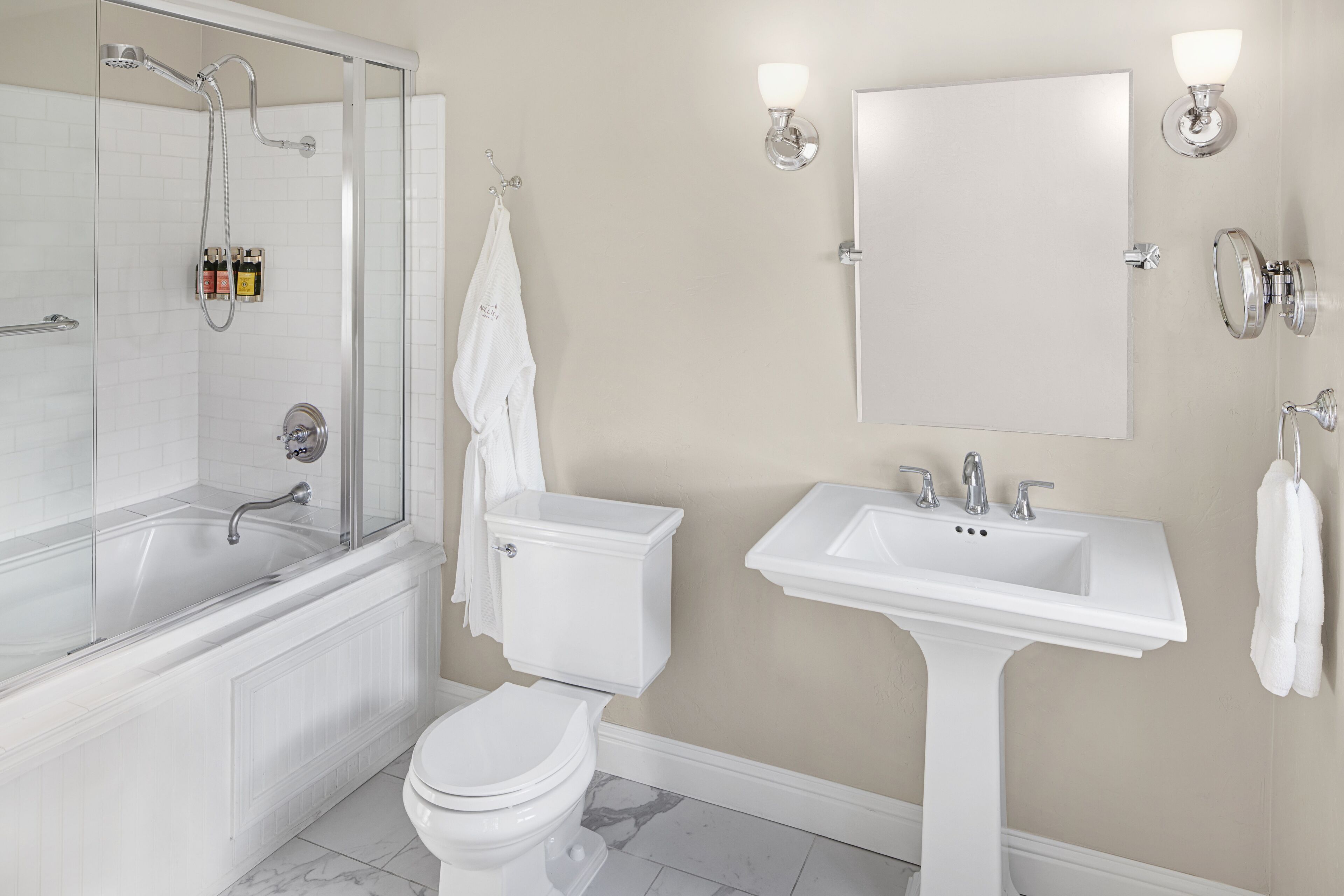Un baño moderno con ducha de vidrio, lavamanos sobre pedestal y un inodoro.