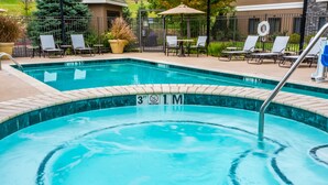 Une piscine rectangulaire bordée de carreaux, avec un poste de surveillance pour les sauveteurs et des chaises longues disposées tout autour.