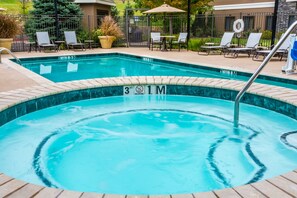 Ein rechteckiger Pool mit Fliesenrand, einer Rettungswache und Liegestühlen rundherum.