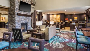 Un hall d’hôtel doté d’une cheminée en pierre, d’espaces aménagés pour se détendre, d’un bar et d’un espace repas.