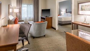 Une chambre d’hôtel équipée d’un bureau, d’une chaise, d’une télévision, d’un lit et offrant une vue sur l’extérieur.