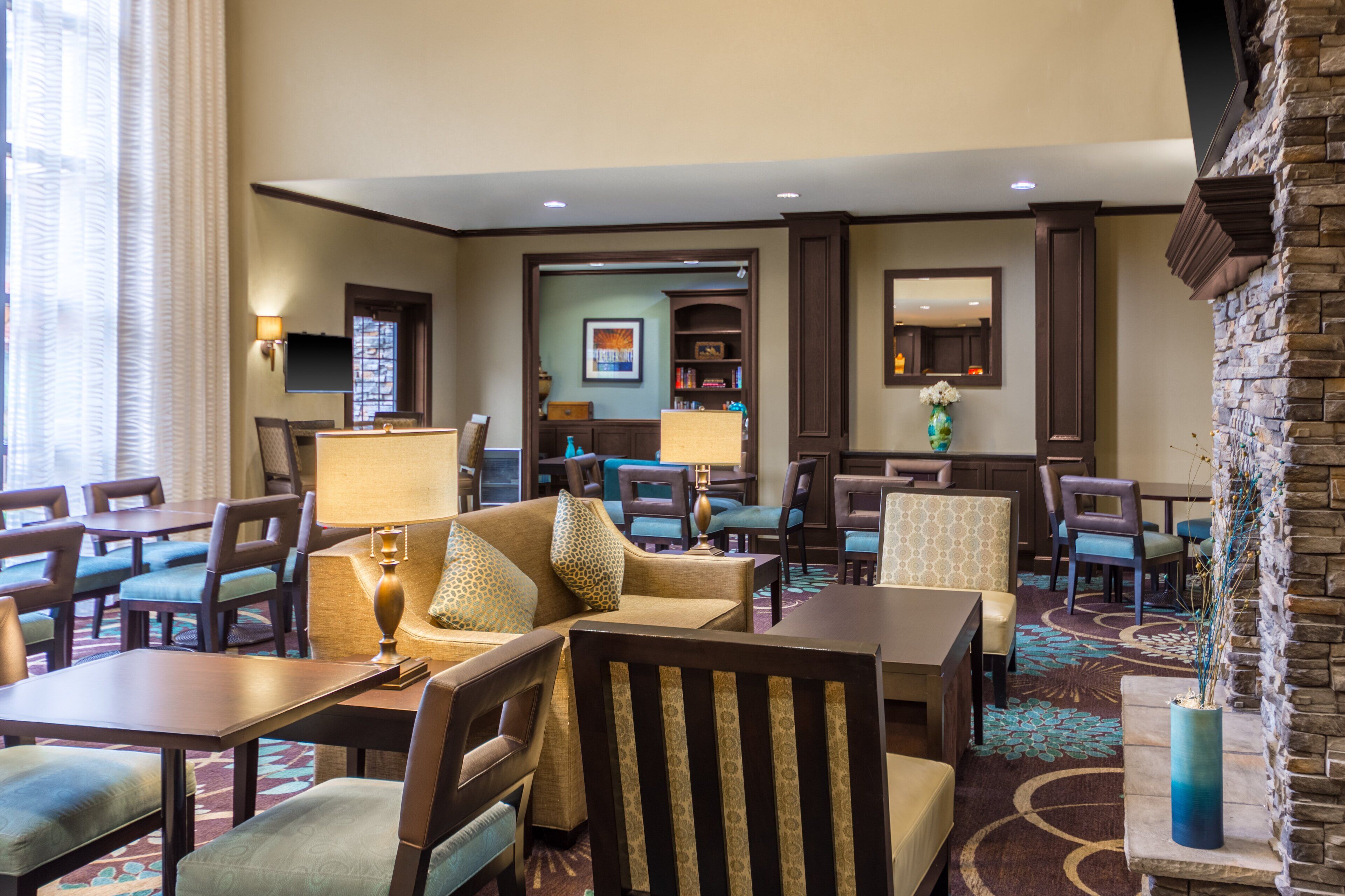 A hotel lobby with a seating area, tables, and a fireplace.